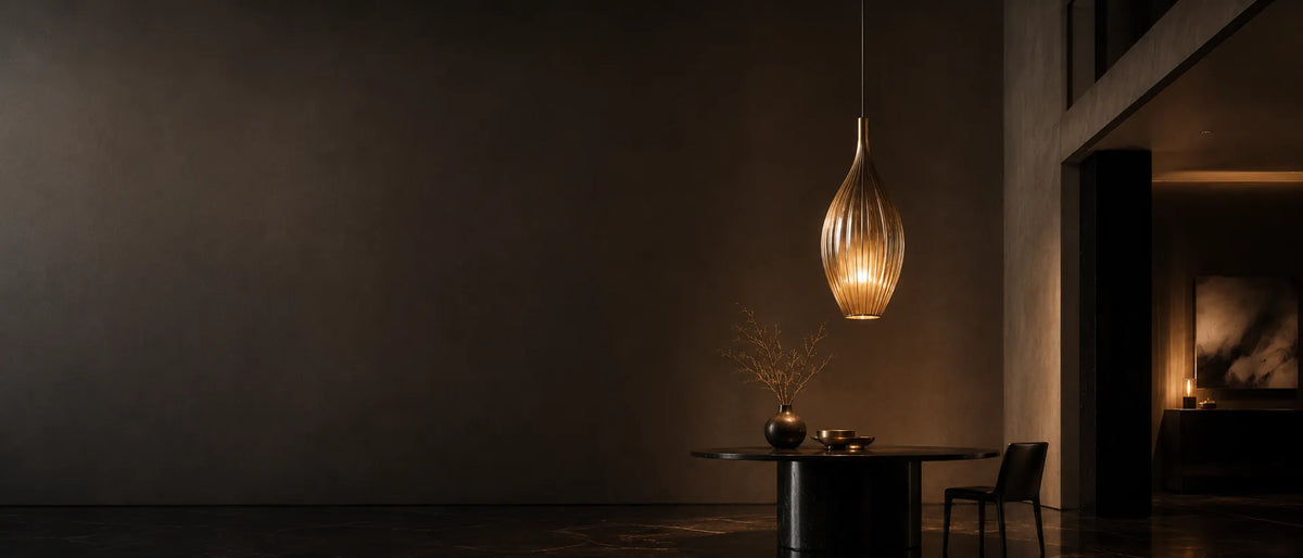 Warm sculptural pendant light in a dark premium dining interior