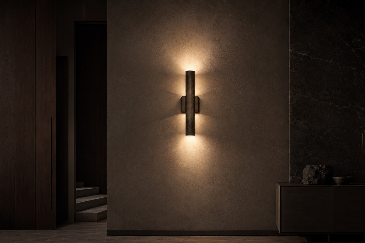 Modern wall sconce casting warm architectural light on textured plaster